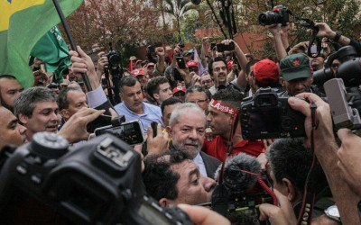 Lula chega à Justiça Federal para prestar depoimento com bandeira do Brasil